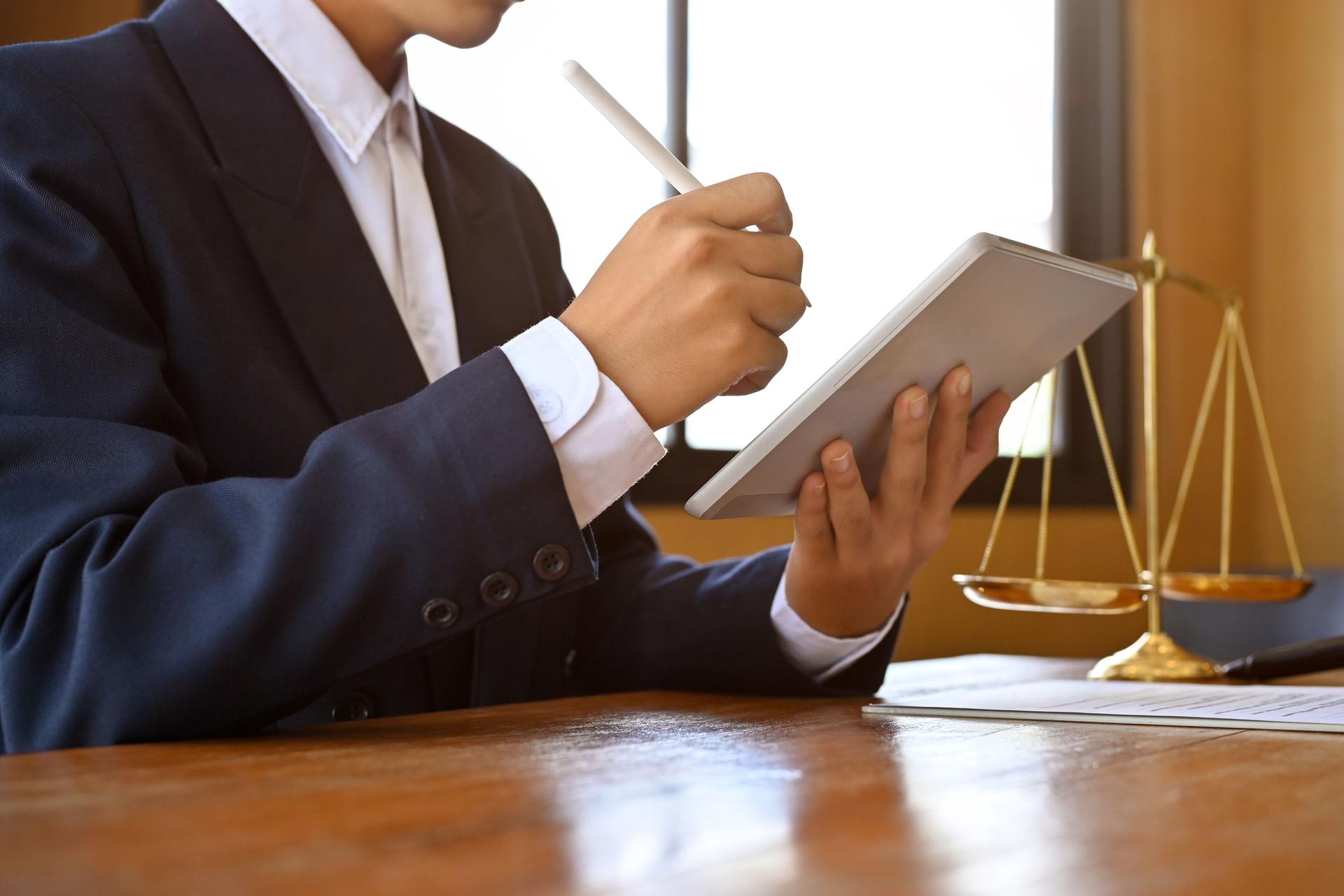 Professional Asian male lawyer or attorney at his office desk, using a digital tablet